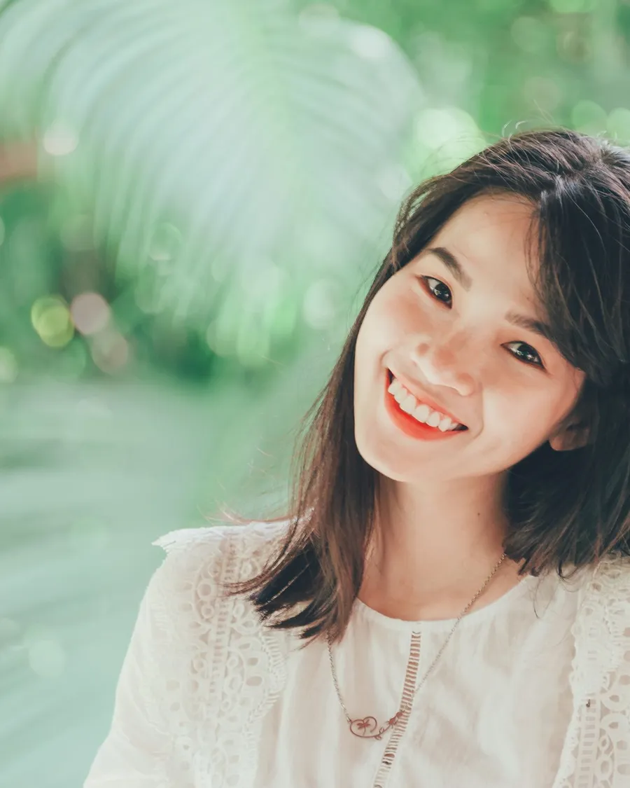 Cô gái mỉm cười giữa vườn cây xanh